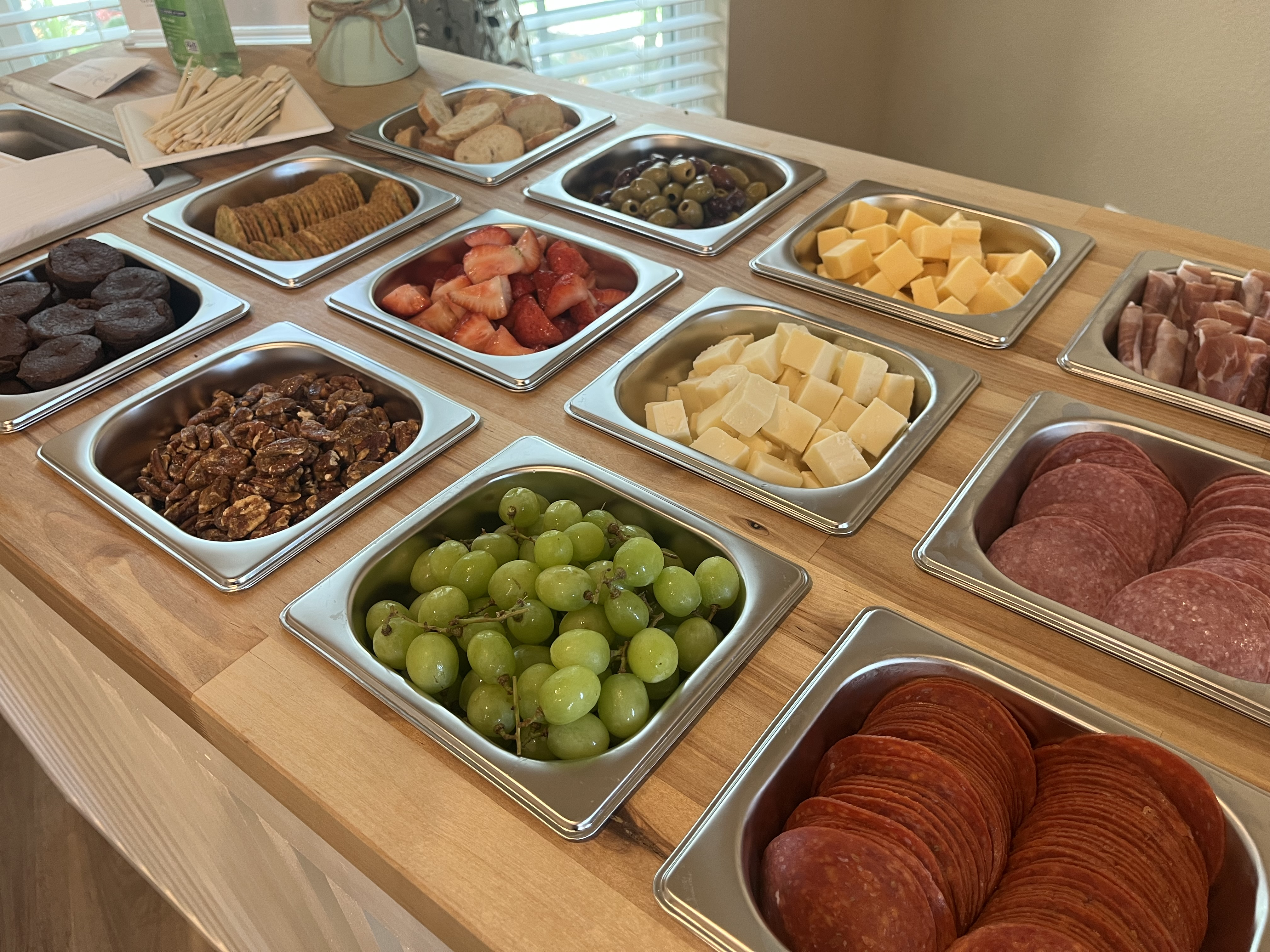 Picture of different types of meats, cheeses, fruits, breads, and desserts in containers set into a countertop