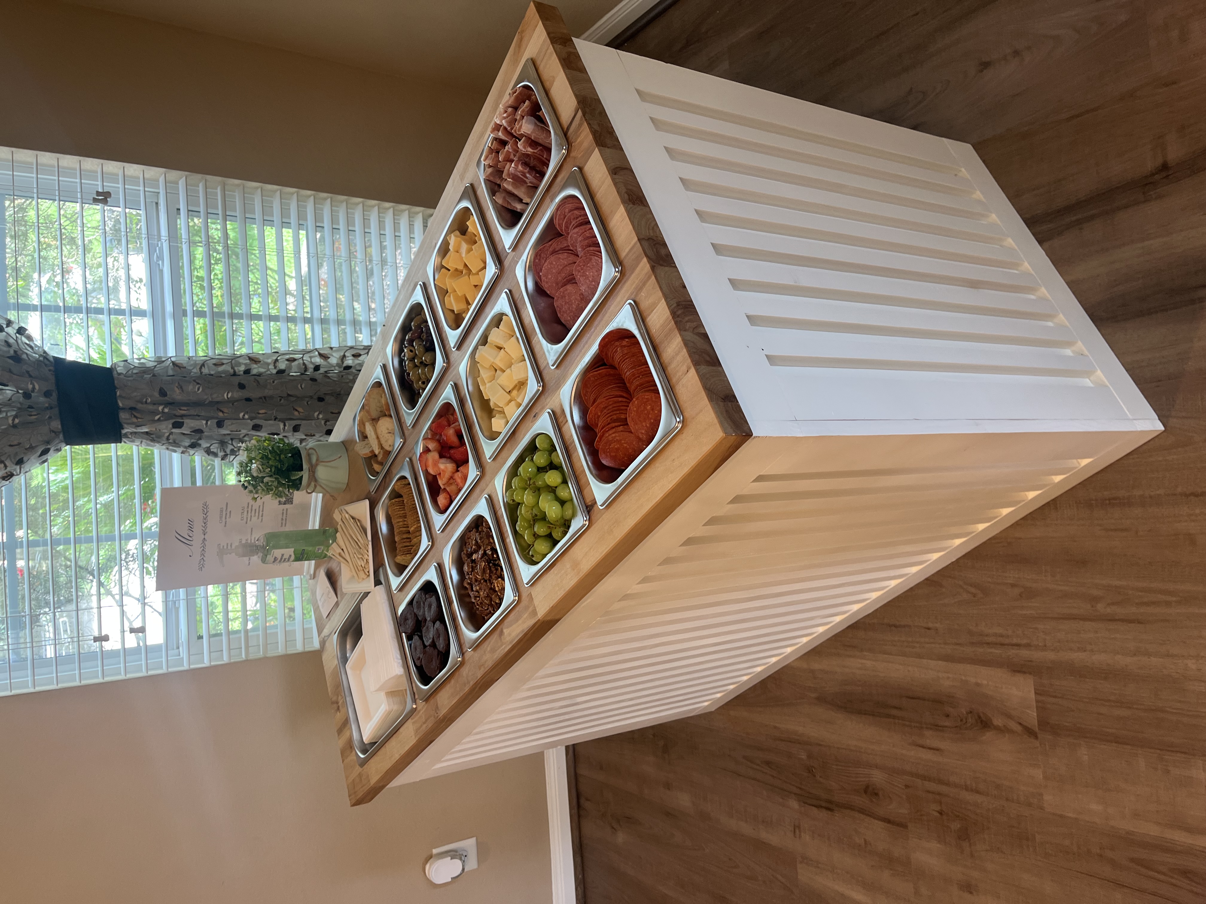 White wooden cabinet with 12 containers set into the countertop with a different food item in each container